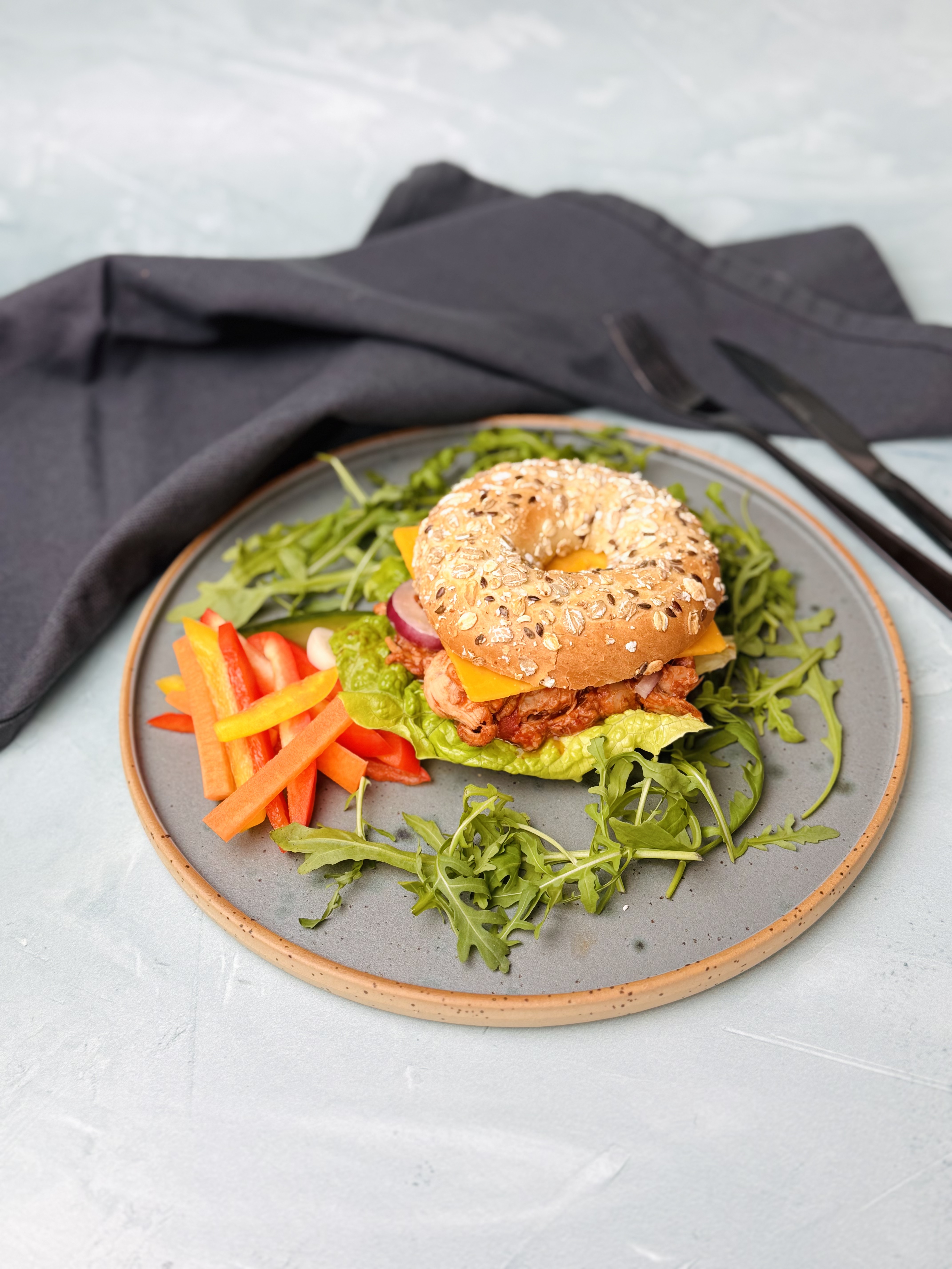 Bajgiel wieloziarnisty z szarpanym kurczakiem w domowym sosie bbq i serem cheddar / chrupiące warzywa