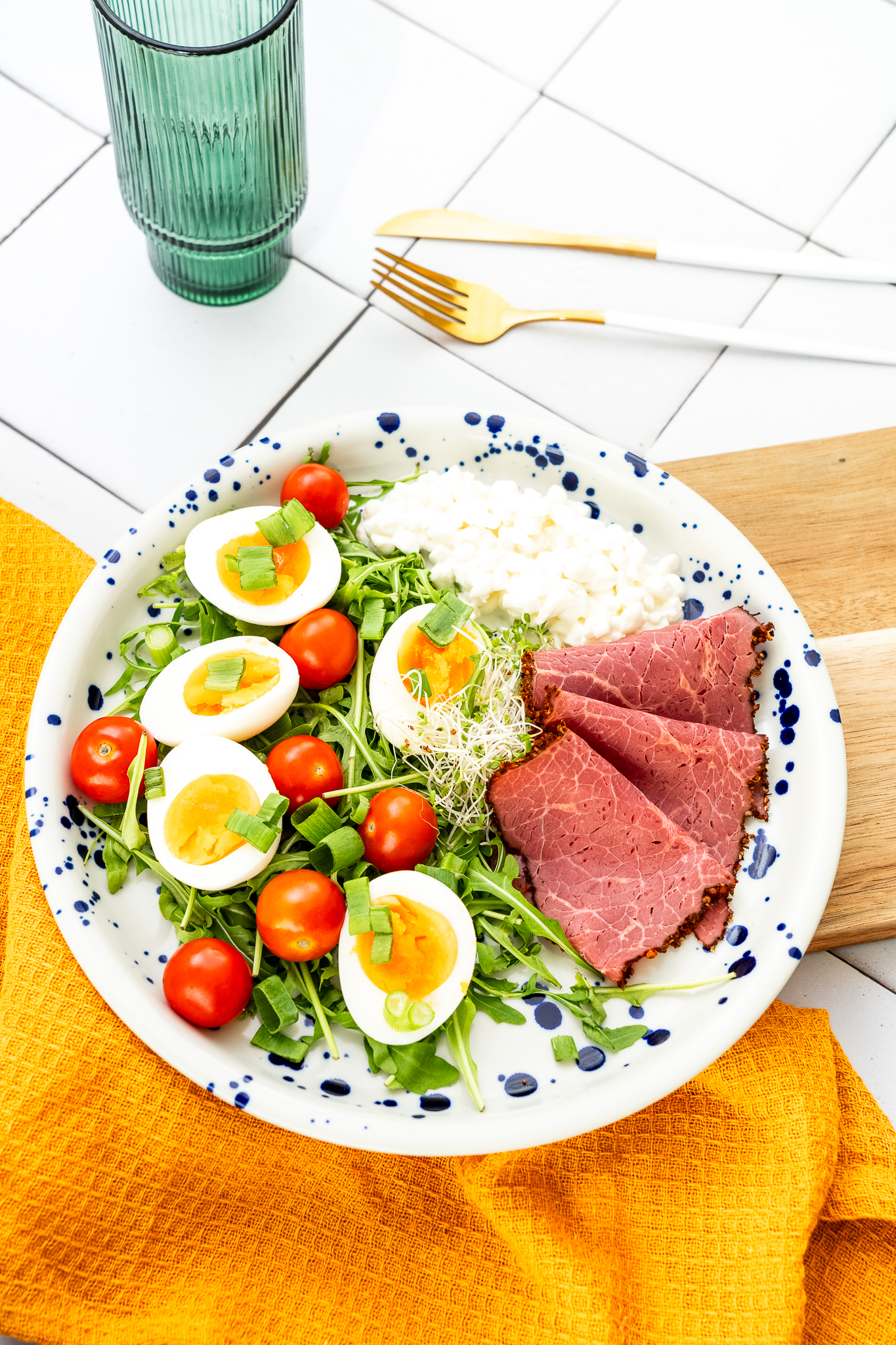 Jajka na miękko z serkiem wiejskim highprotein, szynką wołową, pomidorkiem cherry, rukolą podane z pieczywem żytnim na zakwasie