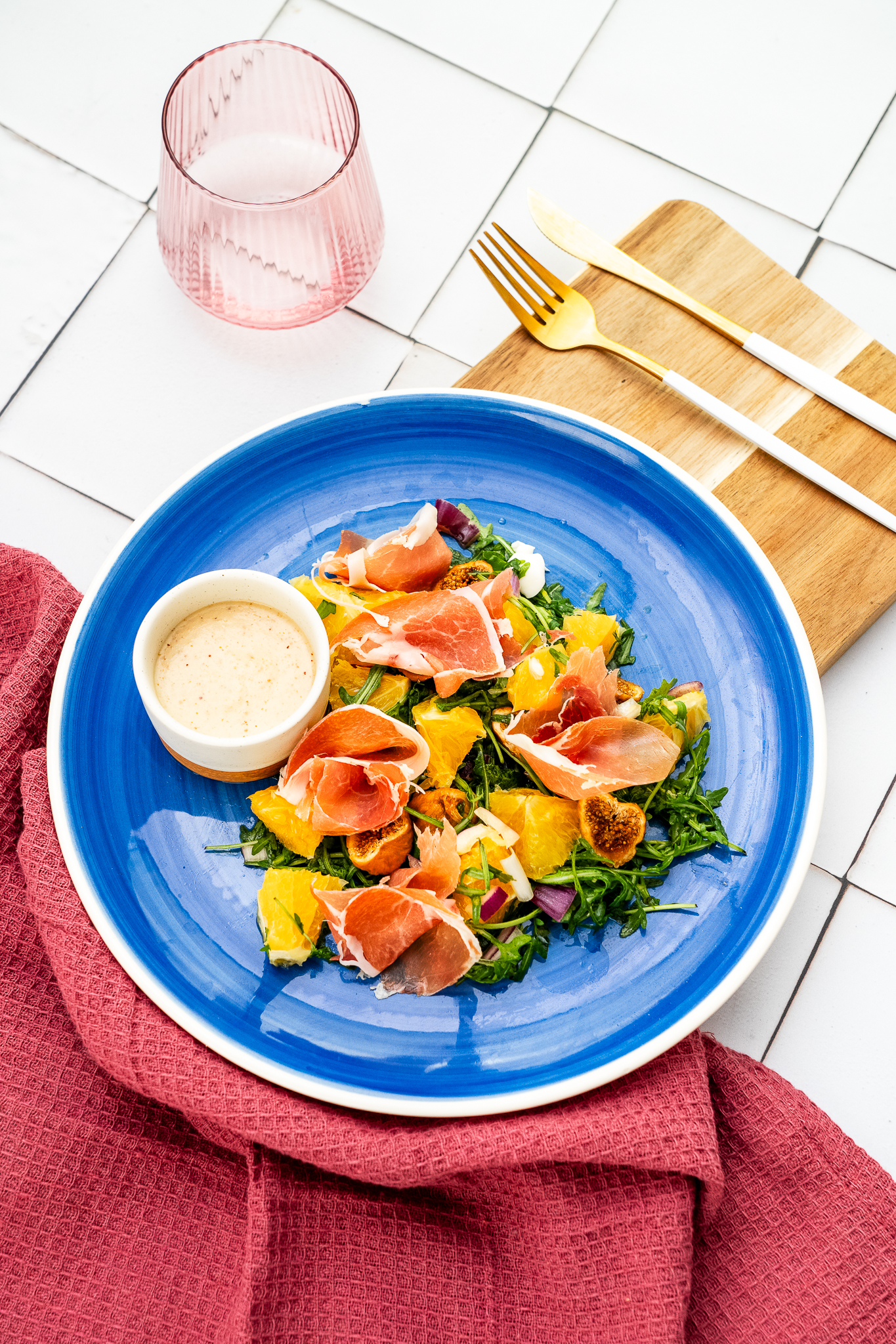 Sałatka z filetowaną pomarańczą, rukolą i szynką parmeńską podana z orzechami i dressingiem figowym